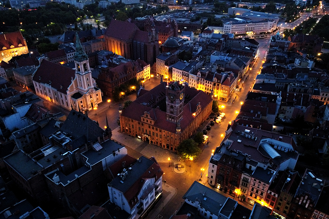 Na zdjęciu widać oświetloną w nocy panorame toruńskiej Starówki. Na środku jest Ratusz Staromiejski. 