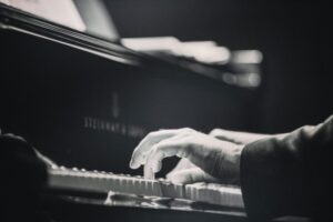 Czarno-białe zdjęcie przedstawiające dłonie grającego pianisty.